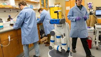 Three researchers in a lab with a robot.